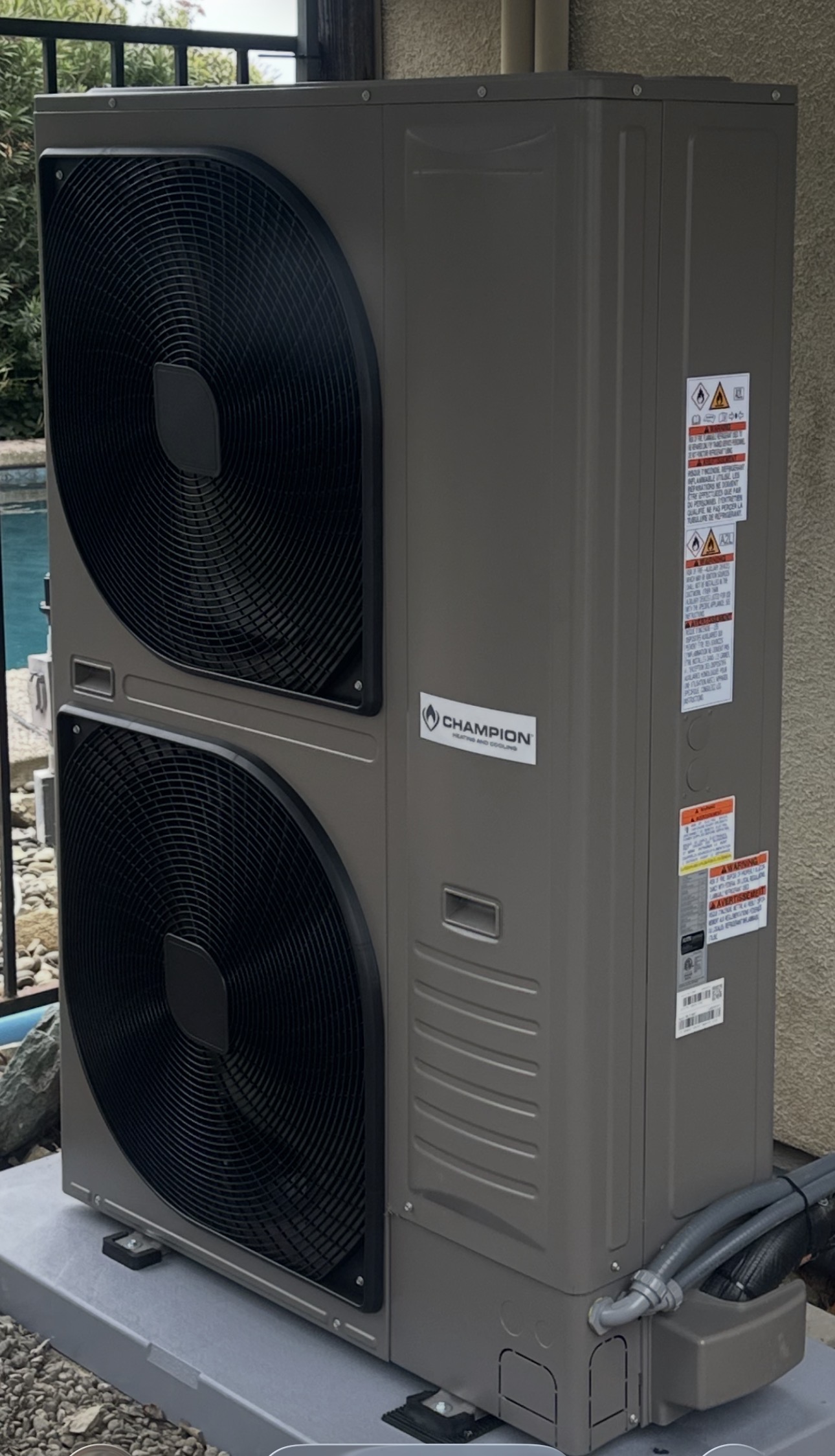 A newly installed dual fan heat pump condenser on a concrete pad beside a pool at an El Dorado Hills home